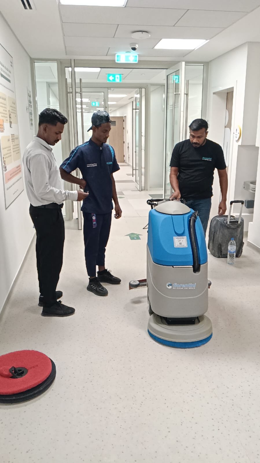 The UAE team reviewing a floor scrubber with an operator on site